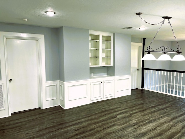 spare room with wainscoting, visible vents, dark wood finished floors, and a textured ceiling