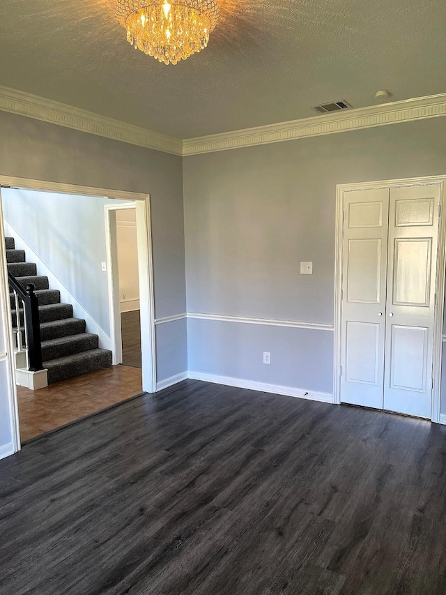 spare room featuring dark wood-type flooring, visible vents, stairway, and an inviting chandelier