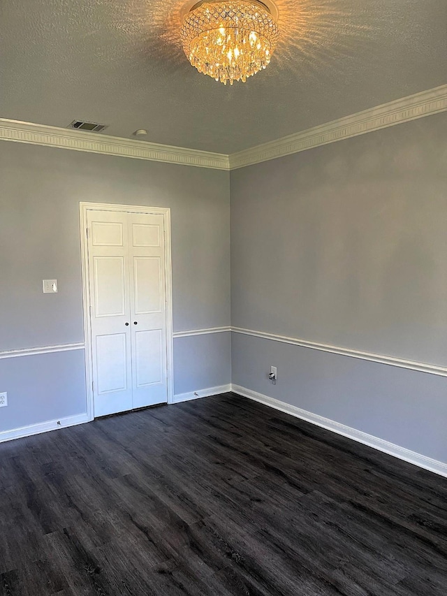 unfurnished bedroom featuring a textured ceiling, a notable chandelier, dark wood-type flooring, visible vents, and baseboards