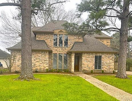 french provincial home with a front lawn and brick siding