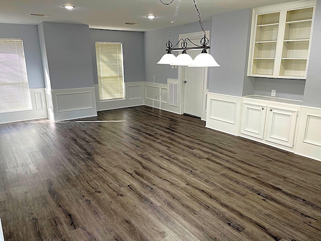 unfurnished dining area with visible vents, dark wood finished floors, and wainscoting