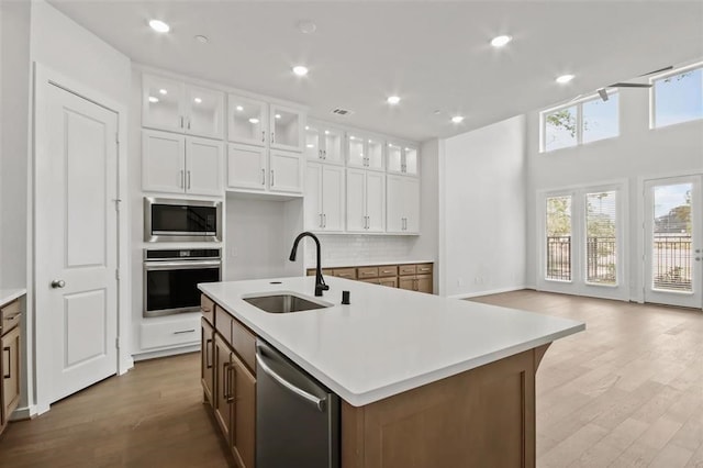 kitchen with a sink, backsplash, wood finished floors, stainless steel appliances, and light countertops