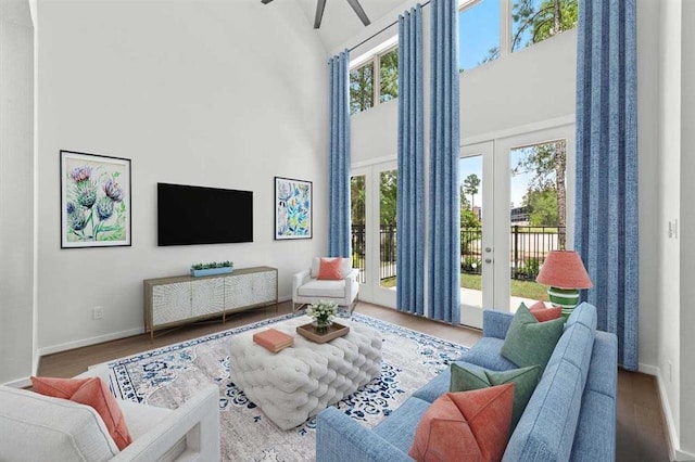 living area with plenty of natural light, a high ceiling, baseboards, and wood finished floors