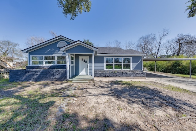 view of front of property with concrete driveway, an attached carport, and stone siding