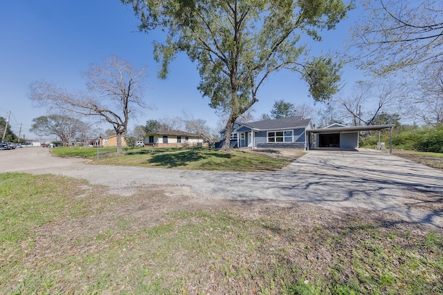 view of front of house featuring driveway, an attached carport, and a front yard