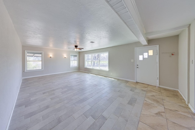 interior space featuring a textured ceiling, ceiling fan, baseboards, and beamed ceiling