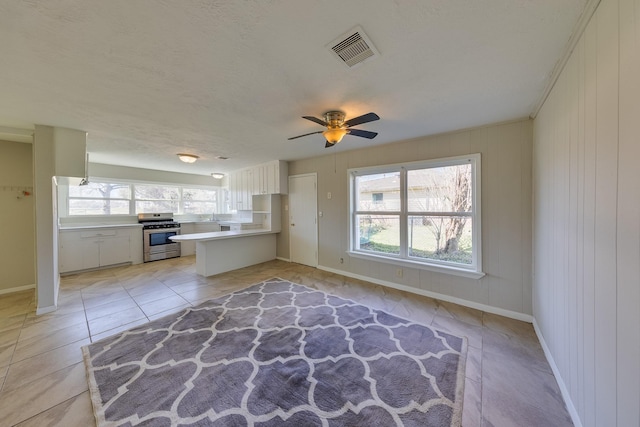 kitchen featuring visible vents, light countertops, white cabinetry, a peninsula, and stainless steel stove