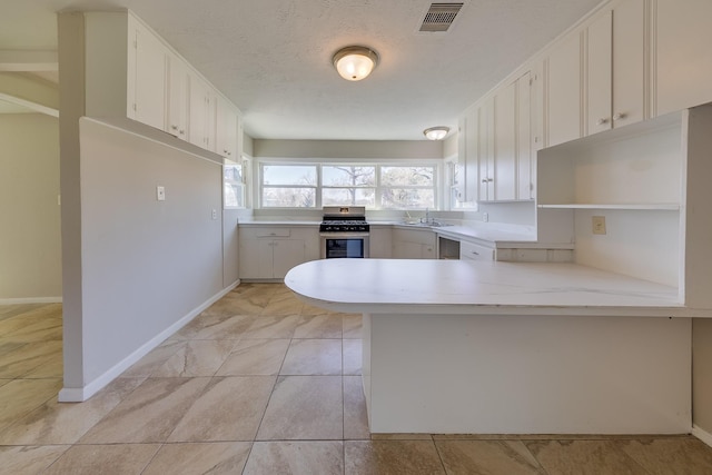 kitchen with light countertops, white cabinetry, visible vents, and a sink