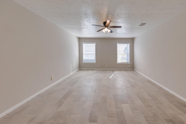 spare room featuring baseboards, ceiling fan, visible vents, and light wood-type flooring