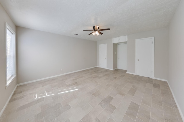 empty room featuring baseboards, visible vents, ceiling fan, and a textured ceiling