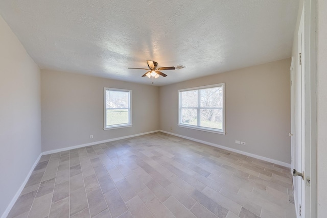 spare room featuring light wood-style flooring, baseboards, a ceiling fan, and a textured ceiling