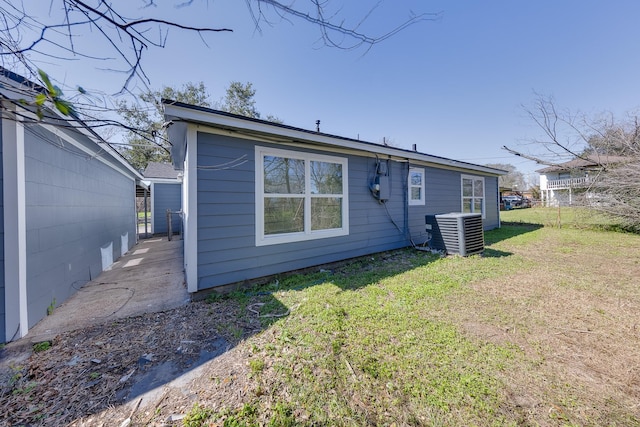 rear view of house with central AC unit and a yard