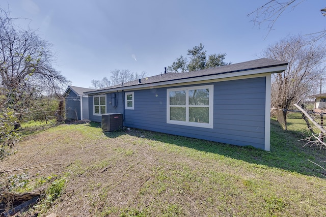 back of property with fence, cooling unit, and a yard