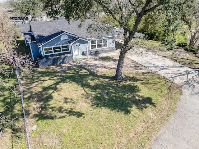 view of front of home with concrete driveway, a front lawn, and a sunroom