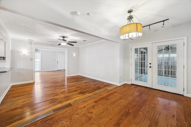 empty room with rail lighting, baseboards, wood finished floors, and french doors