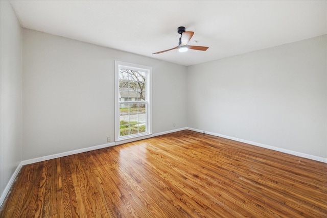 empty room with a ceiling fan, baseboards, and wood finished floors