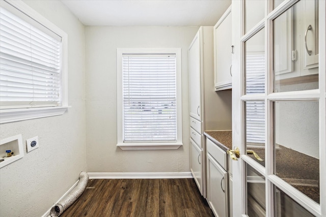 clothes washing area with dark wood-style floors, hookup for a washing machine, cabinet space, electric dryer hookup, and baseboards