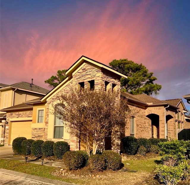 view of property exterior featuring a garage, stone siding, and brick siding