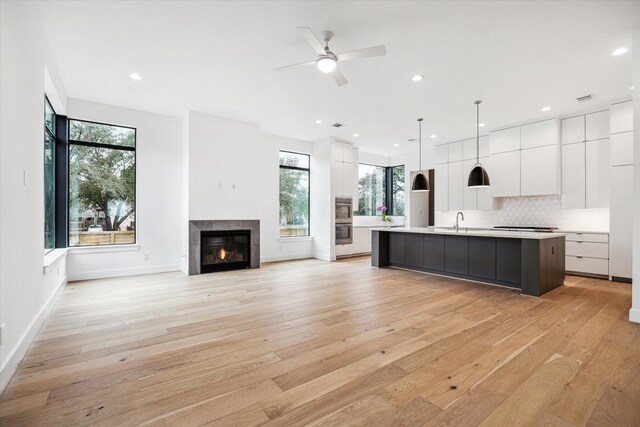 kitchen featuring modern cabinets, light countertops, an island with sink, and white cabinets