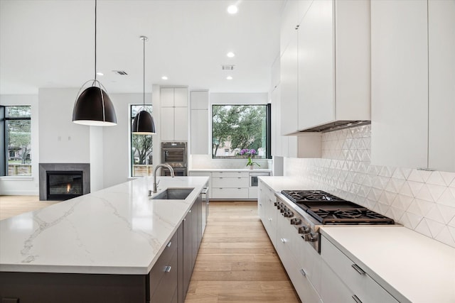 kitchen featuring a center island with sink and white cabinets