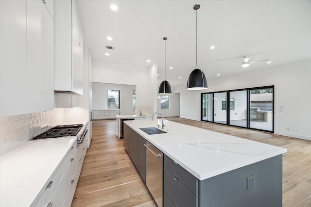 kitchen with a sink, a large island, white cabinetry, and decorative light fixtures