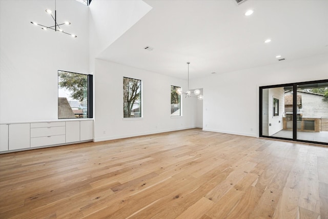 empty room featuring baseboards, recessed lighting, light wood-style flooring, and a notable chandelier