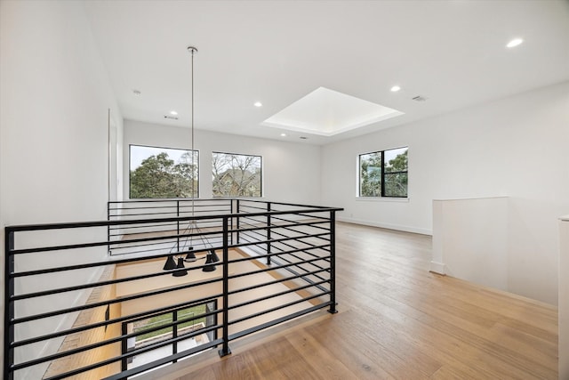 unfurnished room featuring a skylight, baseboards, wood finished floors, a tray ceiling, and recessed lighting