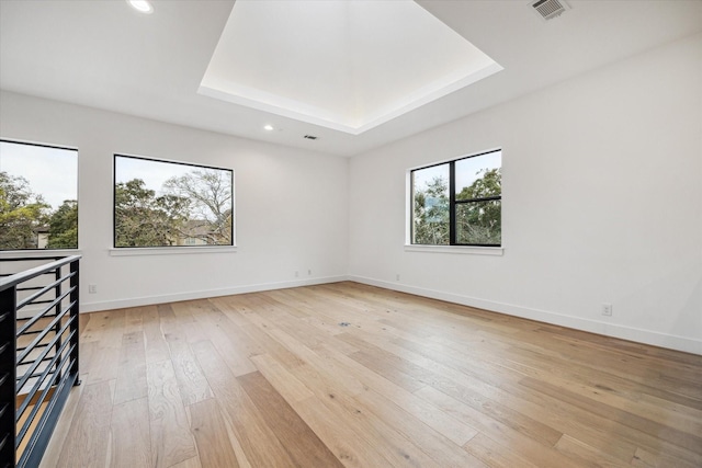 unfurnished room featuring visible vents, baseboards, a tray ceiling, light wood-style floors, and recessed lighting