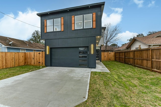 view of front of home featuring a garage, driveway, a front lawn, and a fenced backyard