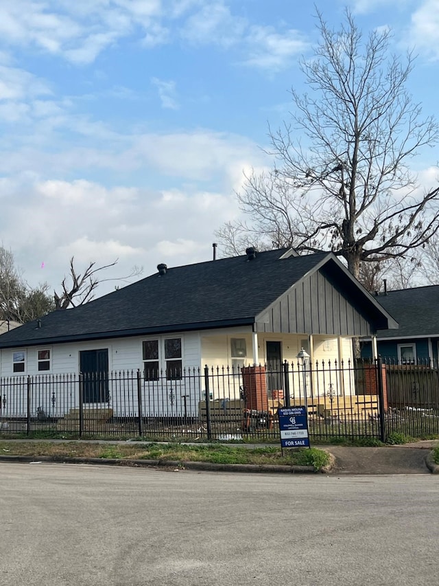 view of front of home featuring board and batten siding, a fenced front yard, and a shingled roof