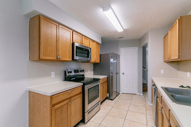 kitchen with a sink, visible vents, light countertops, a textured ceiling, and stainless steel appliances