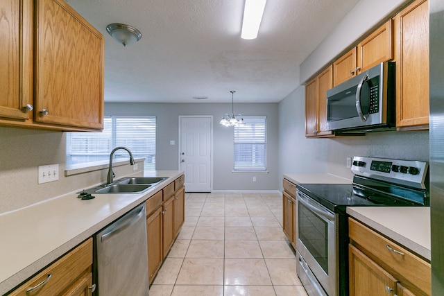 kitchen with appliances with stainless steel finishes, light countertops, a healthy amount of sunlight, pendant lighting, and a sink