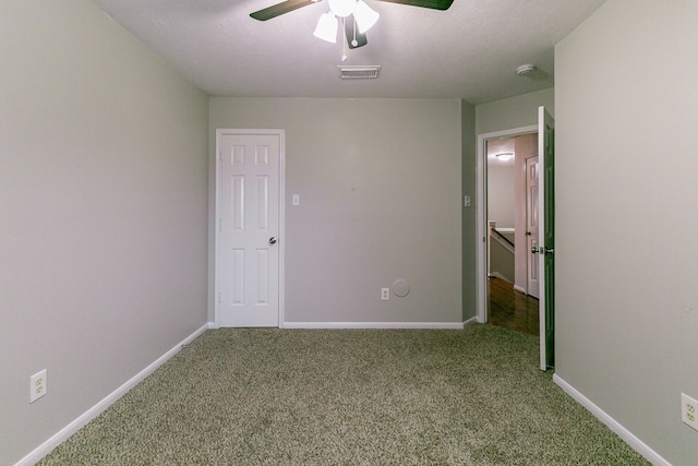 carpeted empty room with baseboards, visible vents, ceiling fan, and a textured ceiling