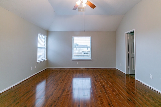 spare room with vaulted ceiling, visible vents, dark wood-style flooring, and baseboards