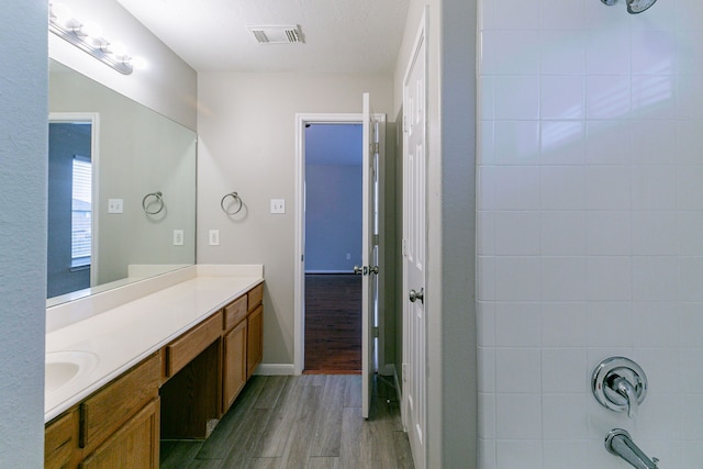 bathroom with visible vents, tub / shower combination, wood finished floors, and vanity