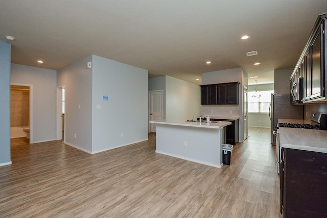 kitchen with visible vents, an island with sink, stainless steel appliances, light countertops, and light wood-type flooring