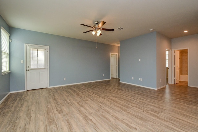 unfurnished room with baseboards, visible vents, a ceiling fan, and light wood-style floors