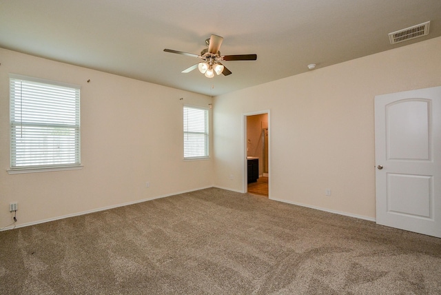 unfurnished room featuring baseboards, carpet, visible vents, and a ceiling fan