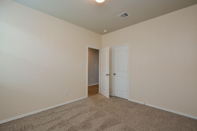 carpeted spare room with visible vents and baseboards