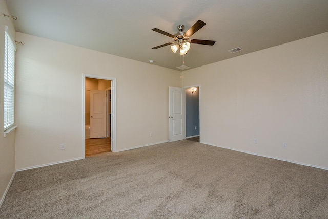 unfurnished room featuring carpet floors, a ceiling fan, visible vents, and baseboards