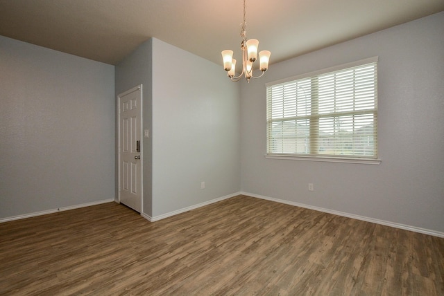 unfurnished room featuring dark wood-style floors, baseboards, and an inviting chandelier