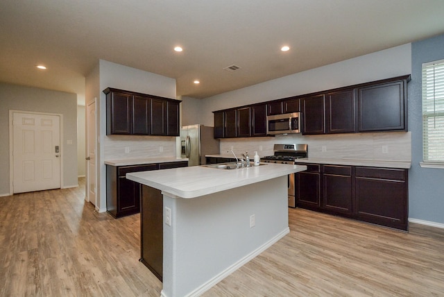 kitchen featuring a center island with sink, light countertops, appliances with stainless steel finishes, light wood-style floors, and a sink