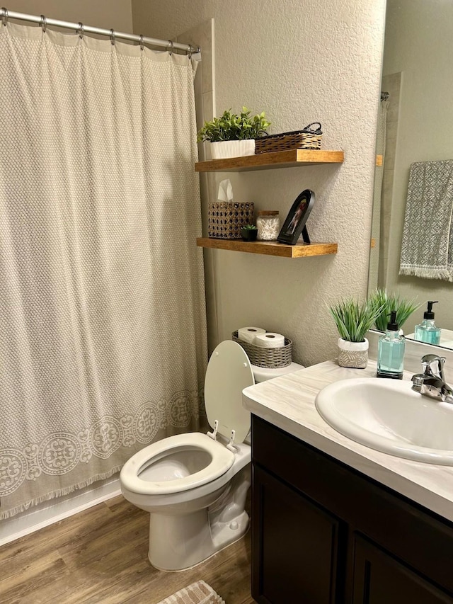 bathroom with a textured wall, vanity, toilet, and wood finished floors