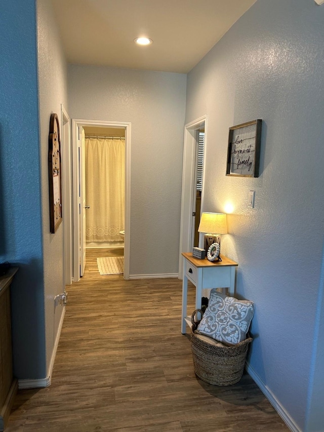 hallway with baseboards, dark wood-style flooring, and a textured wall