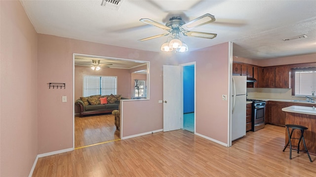 kitchen with stainless steel gas range oven, visible vents, a sink, and freestanding refrigerator