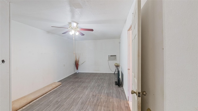 spare room with a wall mounted air conditioner, wood finished floors, and a ceiling fan