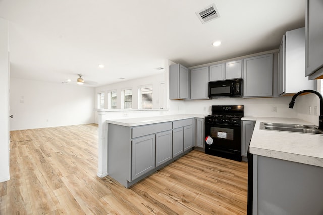 kitchen featuring light countertops, visible vents, gray cabinetry, a sink, and black appliances