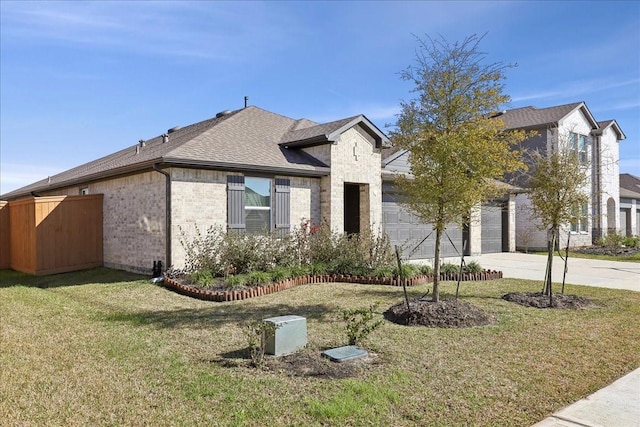 view of front of home with brick siding, a front lawn, roof with shingles, and concrete driveway