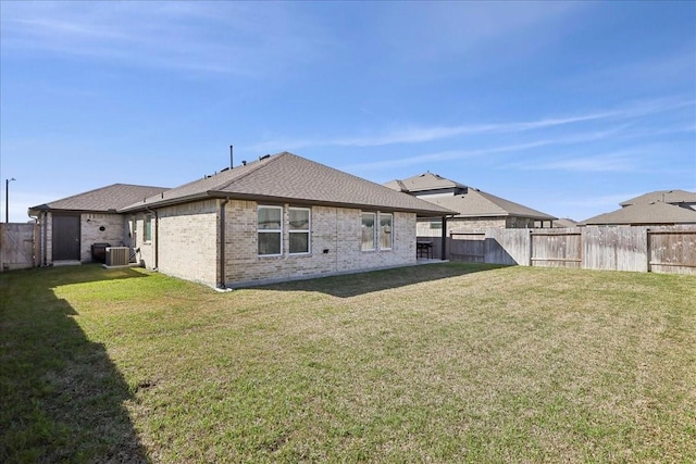 back of house with brick siding, central AC, a fenced backyard, and a yard