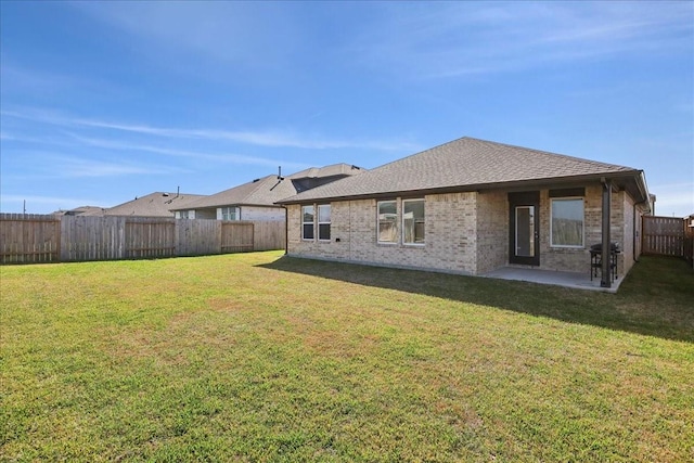 back of property featuring a lawn, a patio, brick siding, a shingled roof, and a fenced backyard